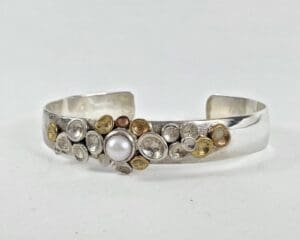 Silver bracelet with pearl and metal accents.