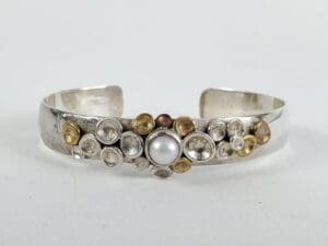 Silver bracelet with pearl and circular accents.