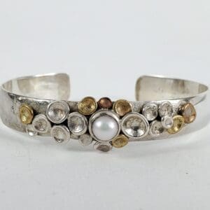 Silver bracelet with pearl and circular accents.