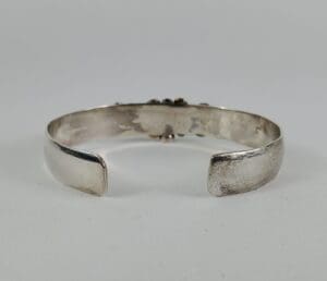 Silver cuff bracelet on white background.