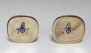 Gold cufflinks with Masonic symbols displayed.