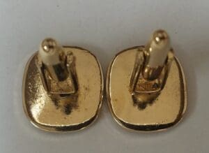 Gold square cufflinks on white background.