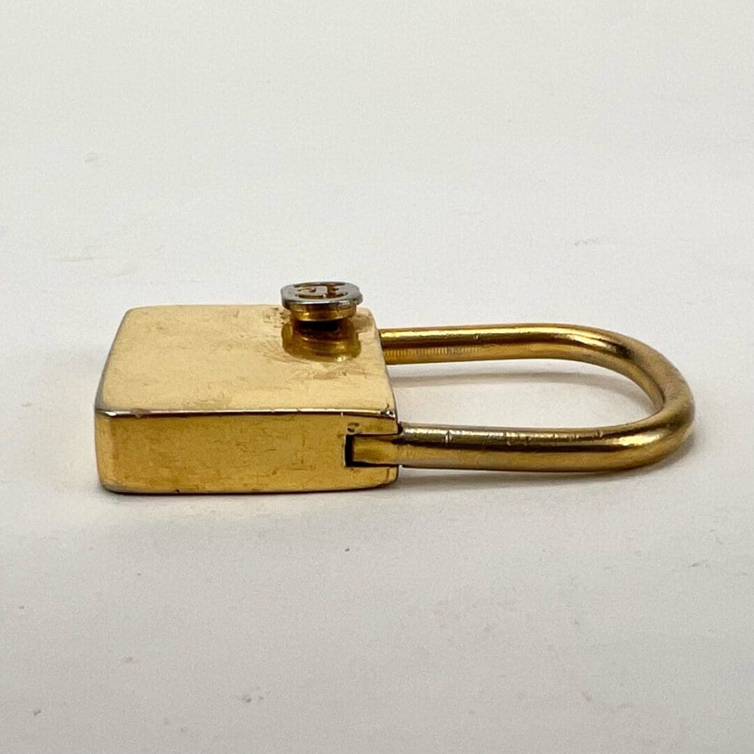 Gold padlock lying on white surface.