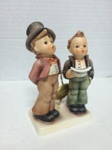 Two ceramic figurines of children standing together.