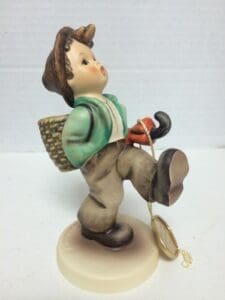 Child figurine walking with backpack and umbrella.