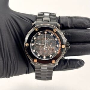 Black-gloved hand holding a luxury watch.
