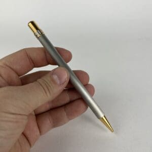 Hand holding a silver and gold pen.