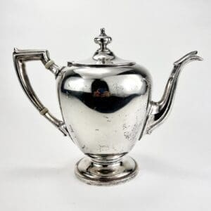 Silver teapot with ornate handle and spout.