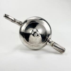 Silver teapot with two handles, top view.
