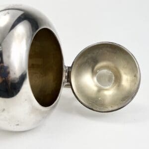Silver teapot with open lid.