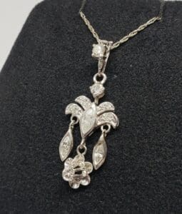 Ornate silver necklace with floral pendant design.