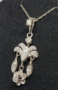 Silver pendant necklace with intricate floral design.