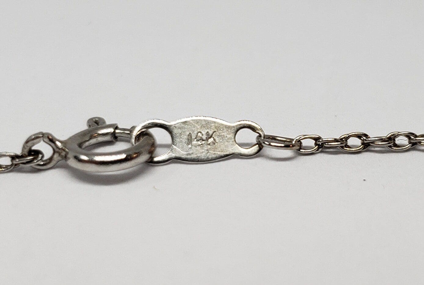 Silver necklace clasp with "14K" marking.