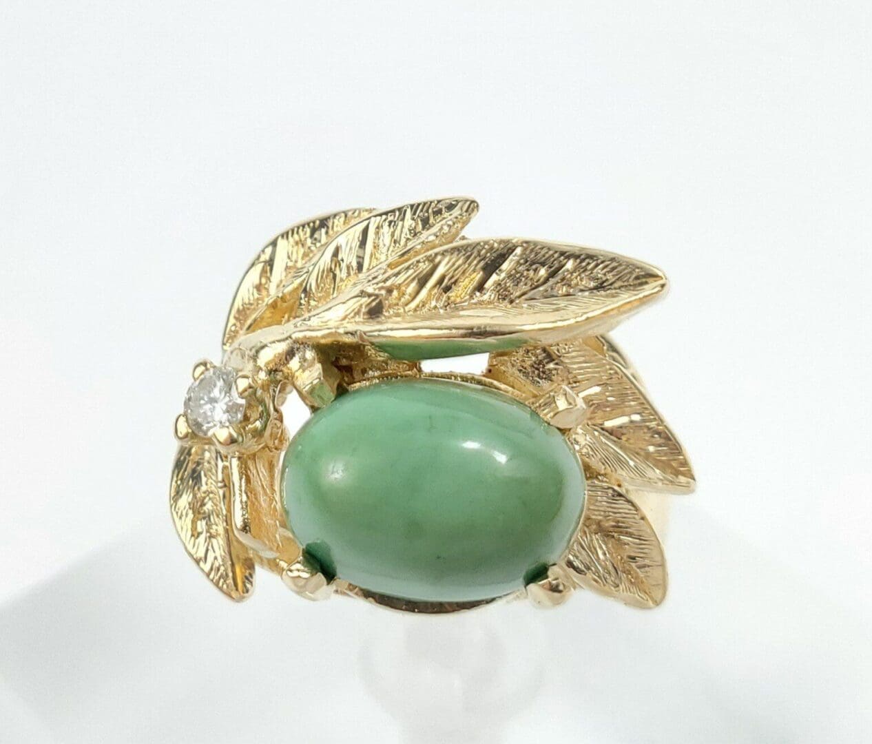 Gold ring with green stone and leaves.