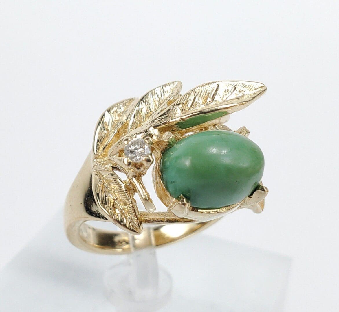 Gold ring with green gemstone and leaf.