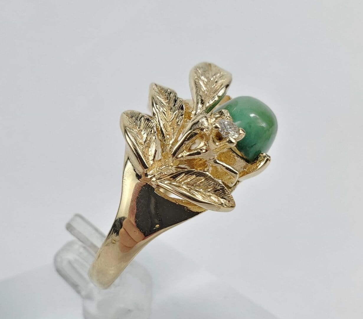Gold ring with green gemstone and leaves.