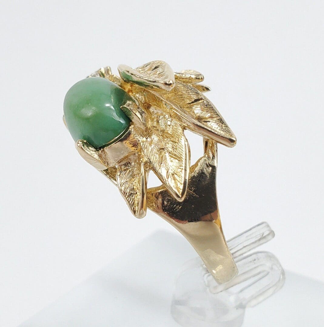 Golden ring with green gemstone and leaf design.
