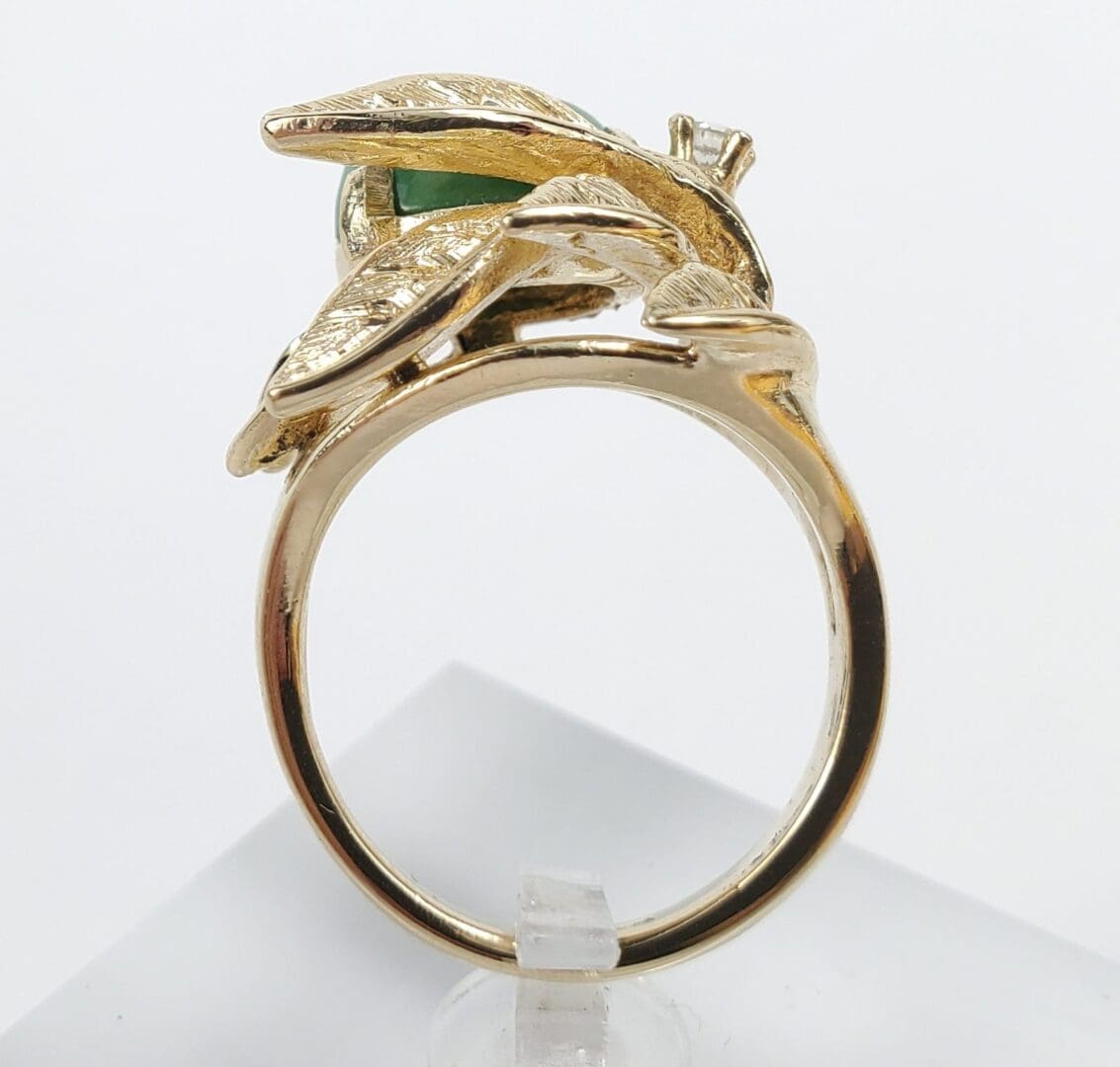 Gold ring with green gemstone and leaves.