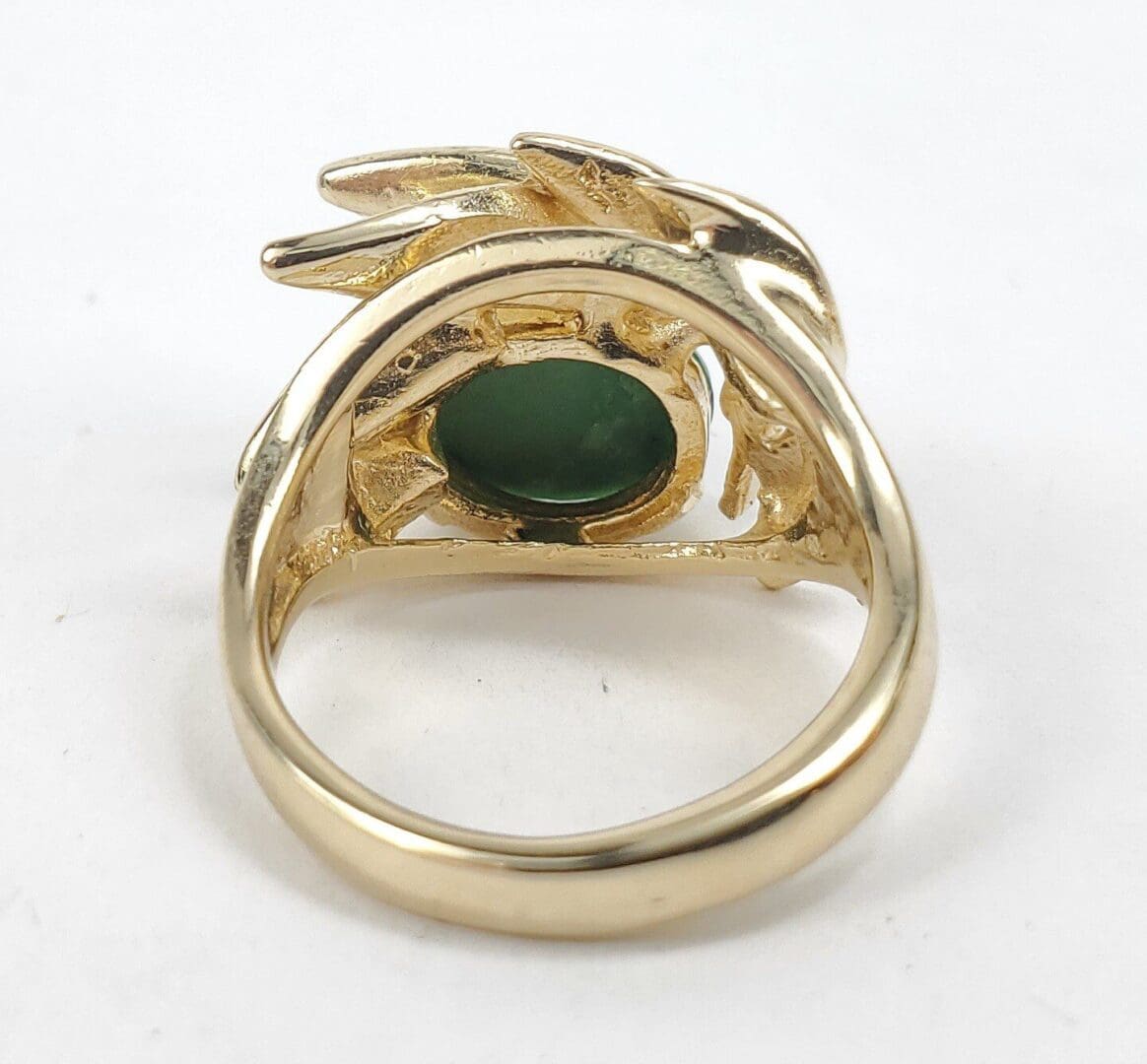 Gold ring with green gemstone, intricate design.
