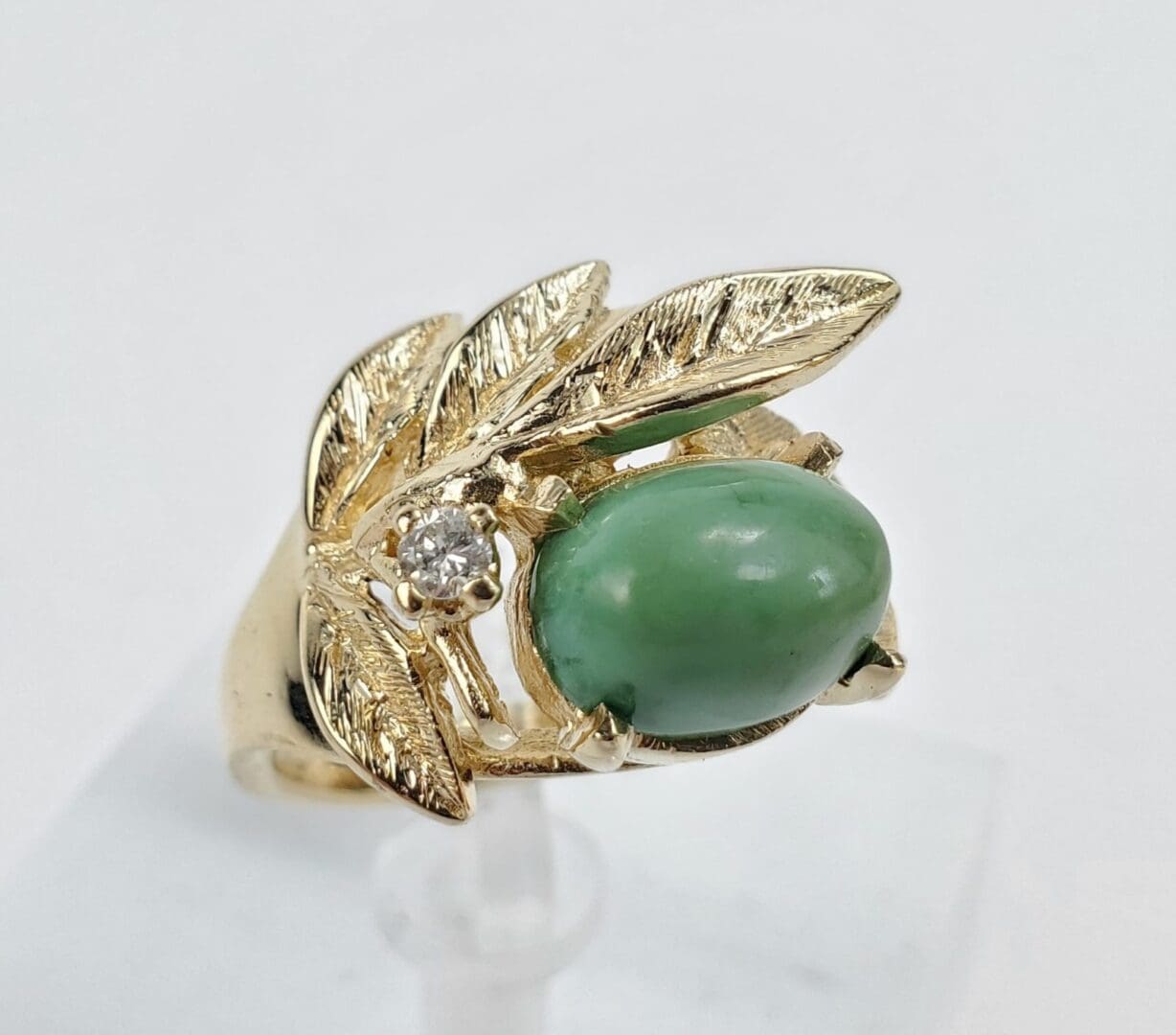 Gold ring with green stone and leaf.