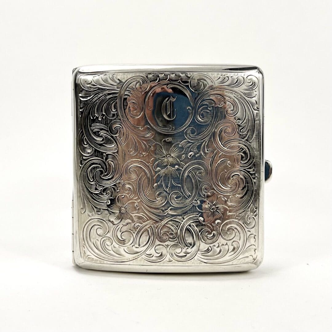 Ornate silver cigarette case with intricate engraving.