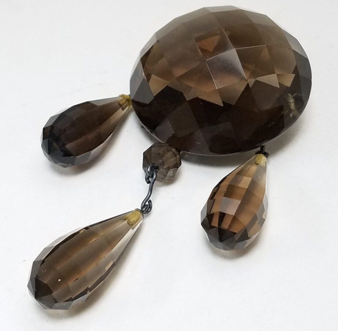 Faceted brown gemstone with teardrop pendants.