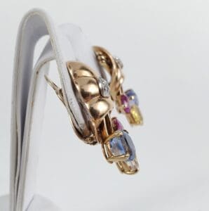 Gold earrings with colorful gemstones displayed.