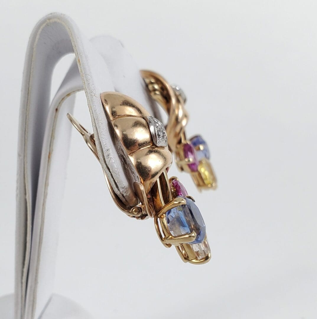 Gold earrings with colorful gemstones displayed.