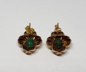 Gold earrings with green gemstones.