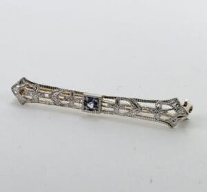 Intricate silver bar brooch with gemstone.
