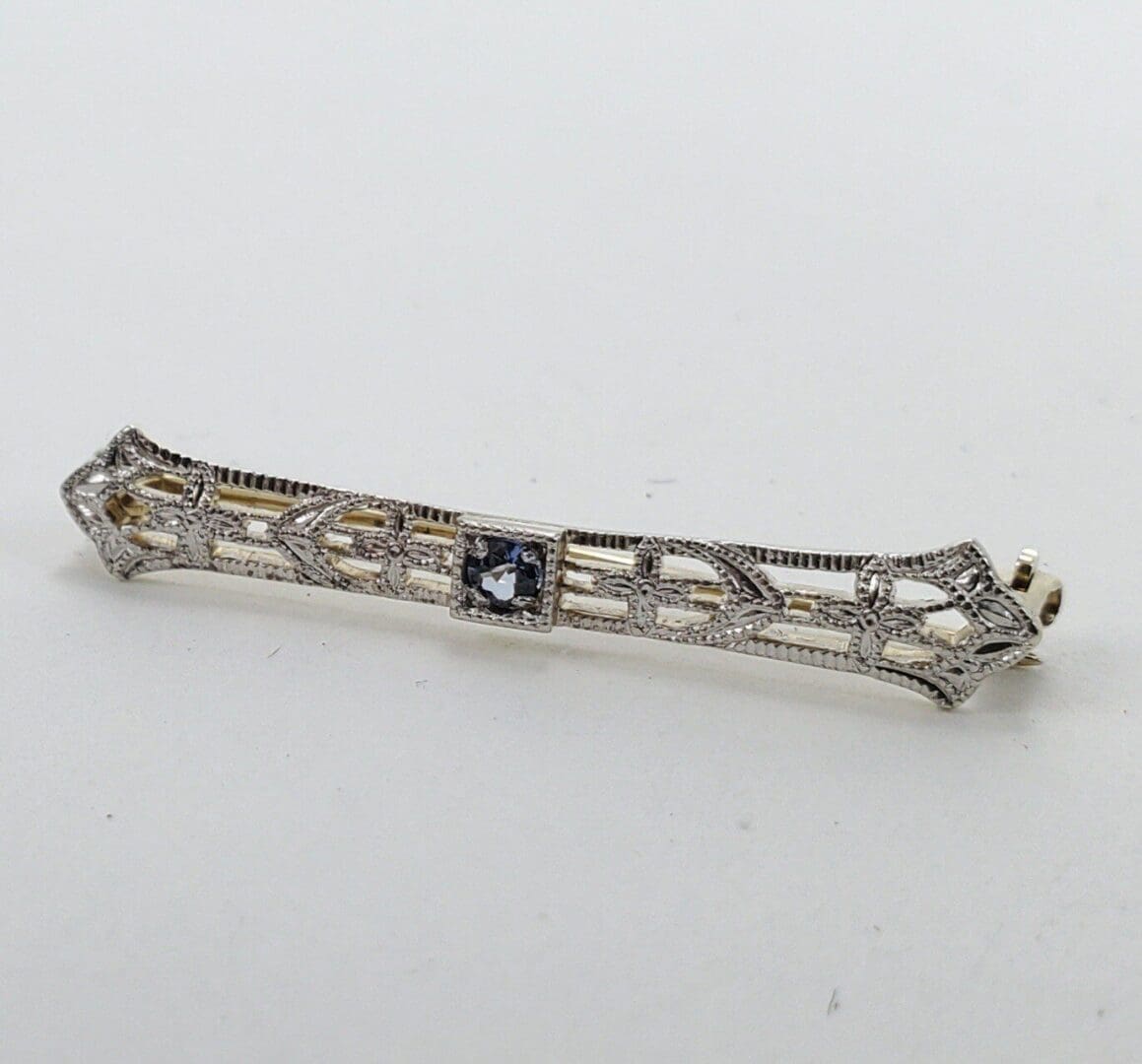 Intricate silver bar brooch with gemstone.