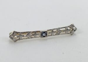Ornate silver brooch with central gemstone.