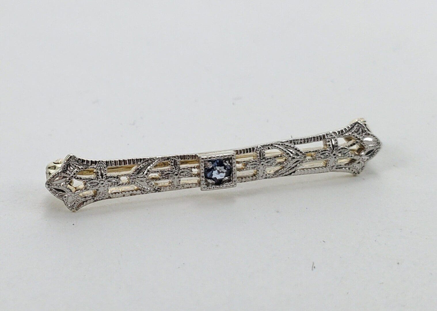 Ornate silver brooch with central gemstone.