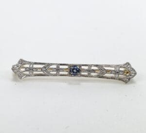 Ornate silver bar brooch with blue stone.
