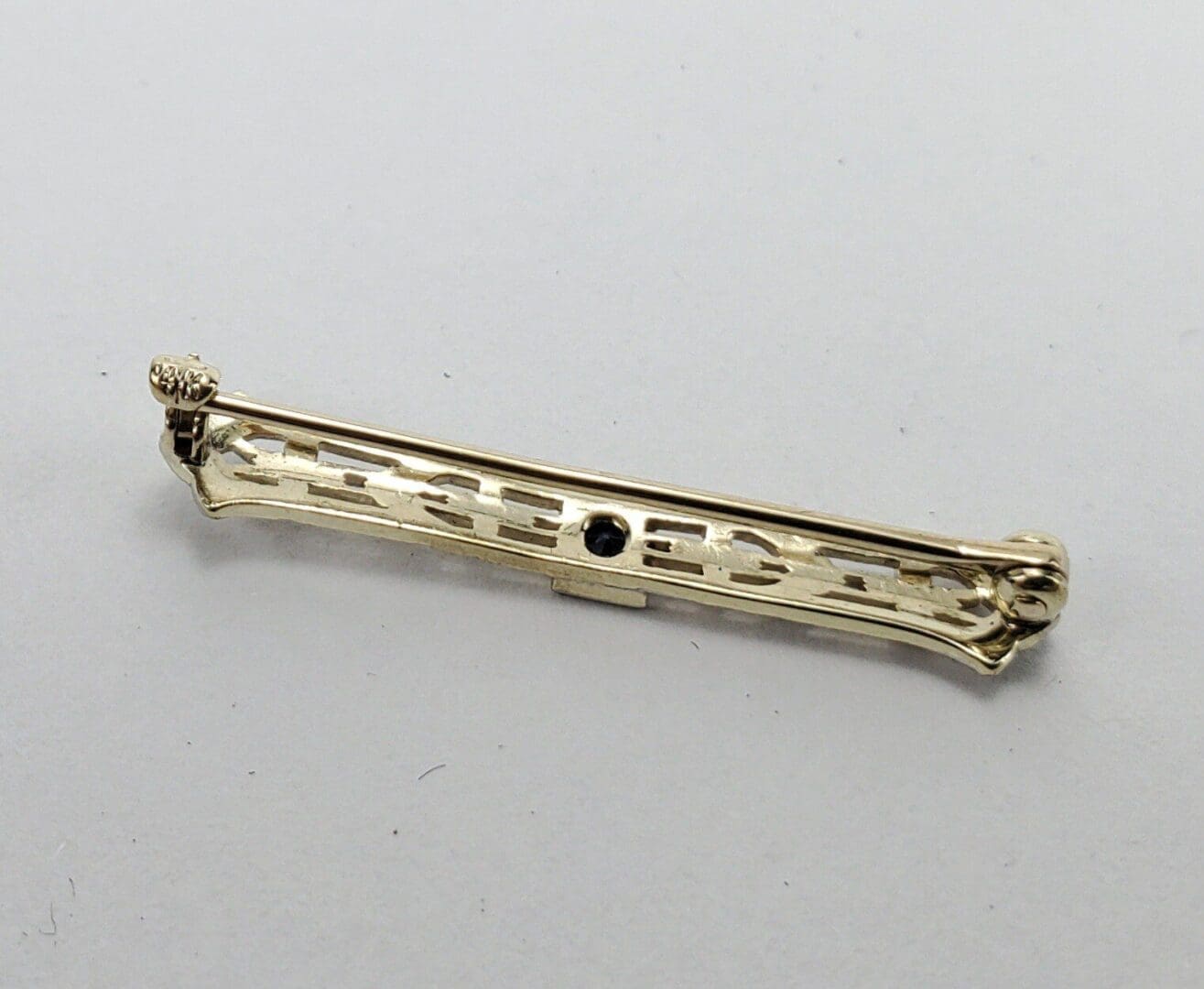 Gold bar brooch with intricate design.