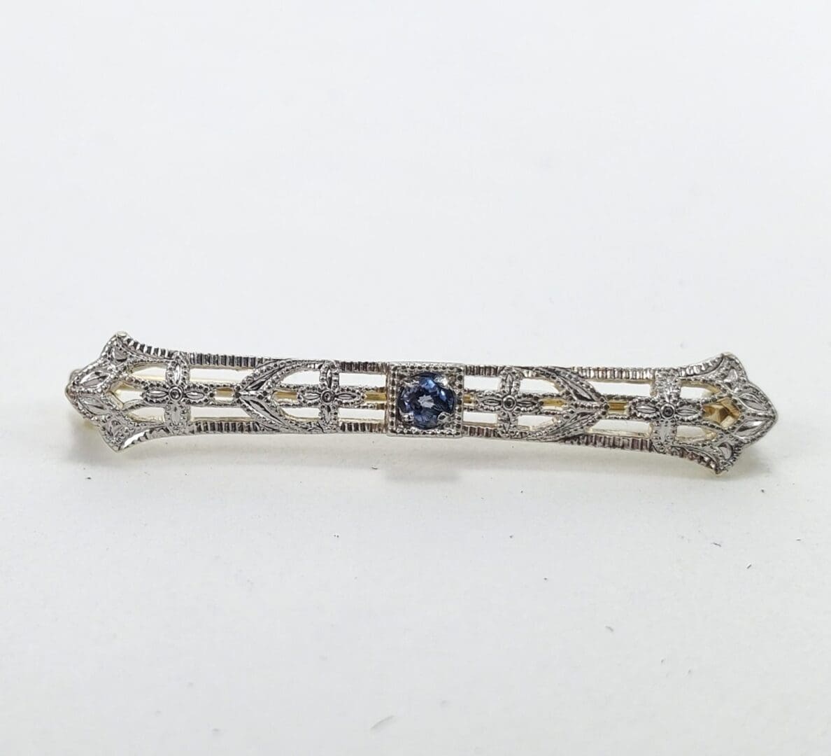 Ornate silver bar brooch with blue stone.