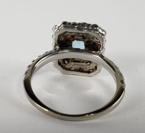 Silver ring with square gemstone setting underside.