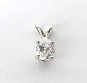 Diamond pendant with silver setting on white.