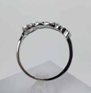 Silver ring with gemstones on display stand.