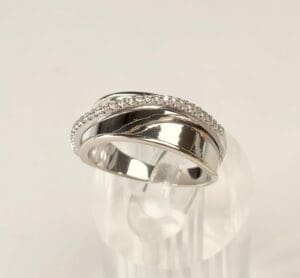 Silver ring with diamond accents on stand.