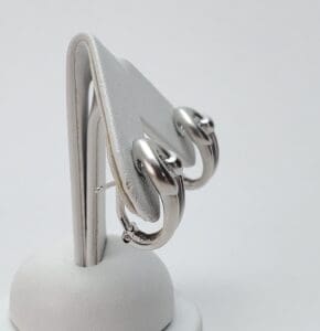Silver hoop earrings on display stand.