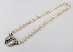Pearl necklace with ornate silver clasp.