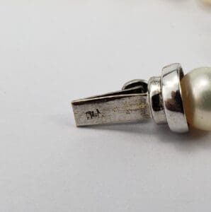 Silver clasp with pearl detail and markings.