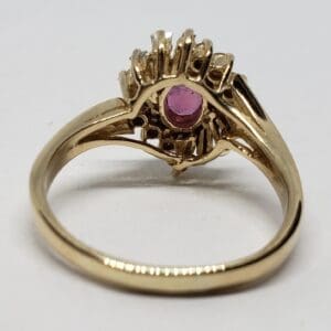Gold ring with pink gemstone, intricate design.