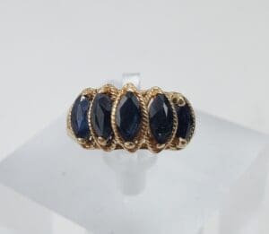 Gold ring with five dark gemstones.