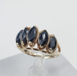 Gold ring with four dark gemstones.