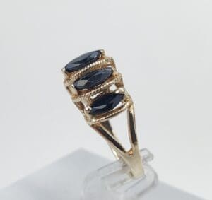 Gold ring with three dark gemstones.