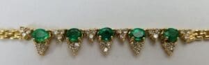 Gold bracelet with emerald and diamond accents.
