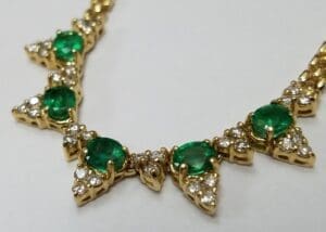 Gold necklace with emerald and diamond accents.