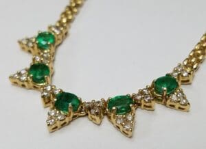 Gold necklace with emerald and diamond stones.